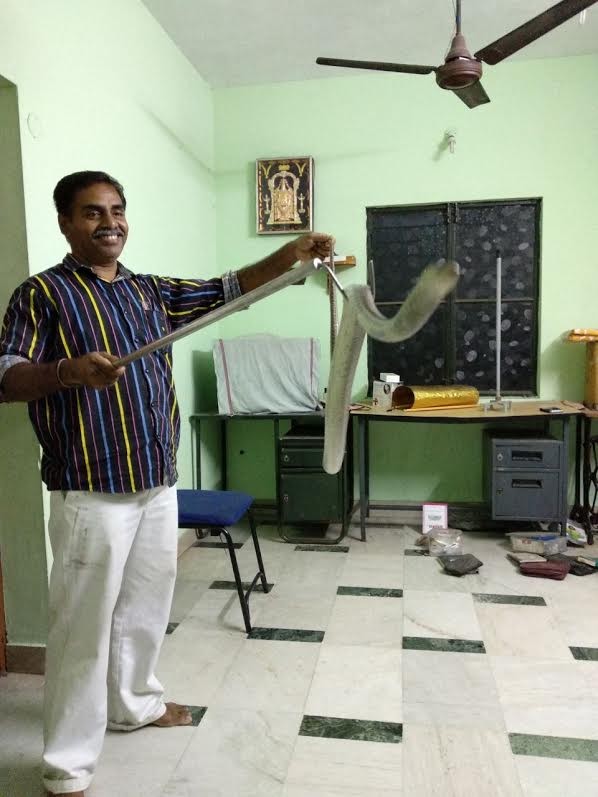 A snake rescuer holding a snake inside a room in Madurai